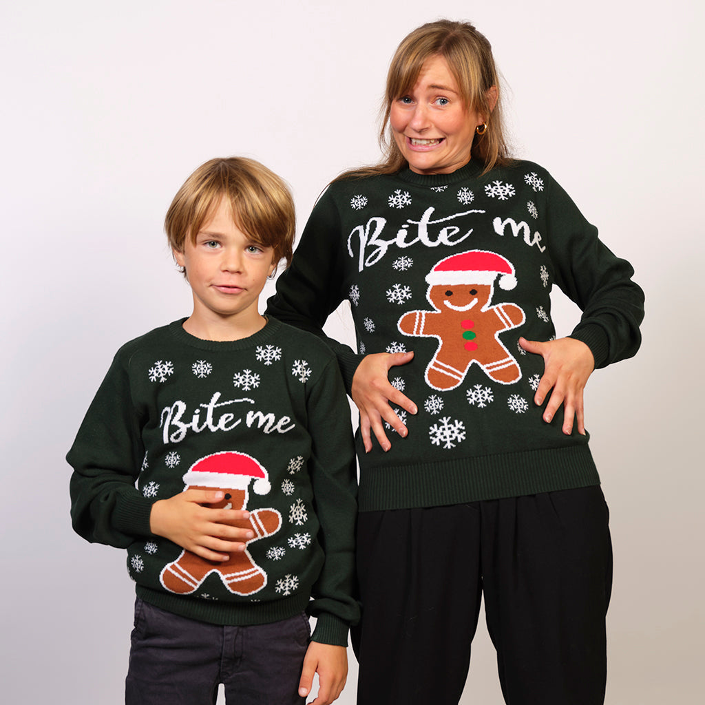 En dame og en dreng, der står og poserer iført en julesweater med en kagemand på.